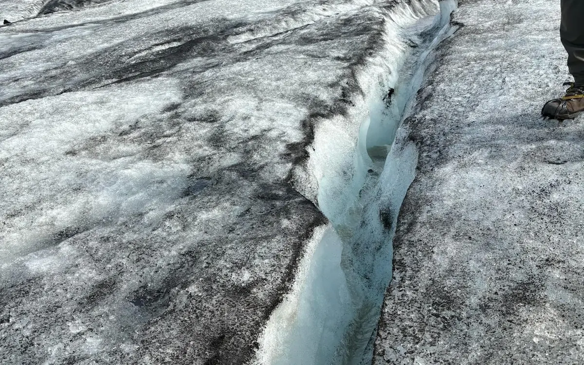Crampons being strapped onto a boot at the edge of a glacier in Iceland