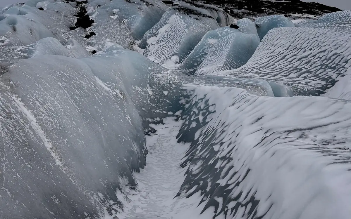 A small guided group of mixed ages walking gentle white ice in crampons and helmets